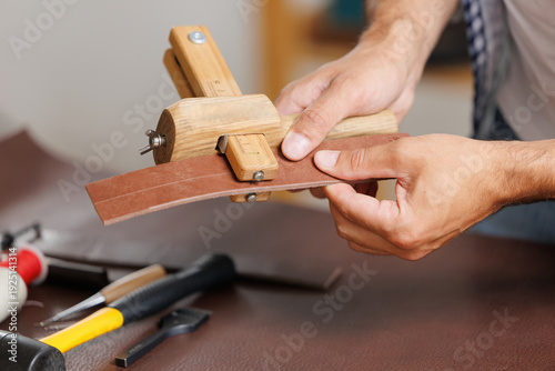 Valokuva Male craftsman working with leather using tailoring tools in workshop for craft
