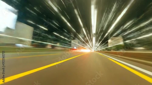 Motion blurred city road at night with light streaks and yellow lane markings