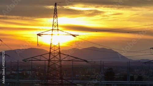 Crane of High-voltage electrical substation switchyard shows transformers and transmission lines during dramatic sunset sky in a rural area.