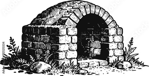 Old stone brick oven with dome shaped arch entrance and surrounding grass and rocks