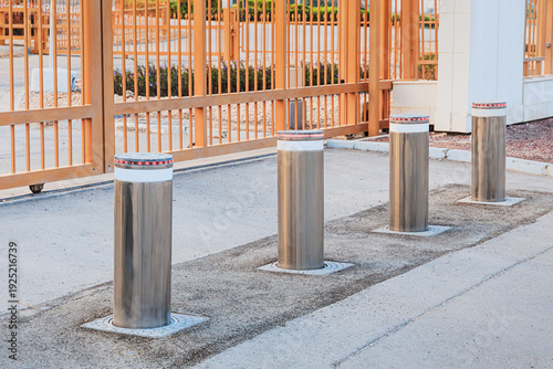 Photos Row of modern automatic retractable bollards rising from asphalt, creating a bar
