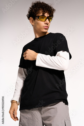 Bild auf Leinwand Stylish curly man in trendy outfit poses confidently in studio setting