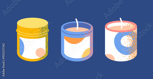 Set of three scented candles in glass jars with geometric labels and speckled decoration. Cylindrical containers with visible wax and wick form a cohesive home fragrance collection.