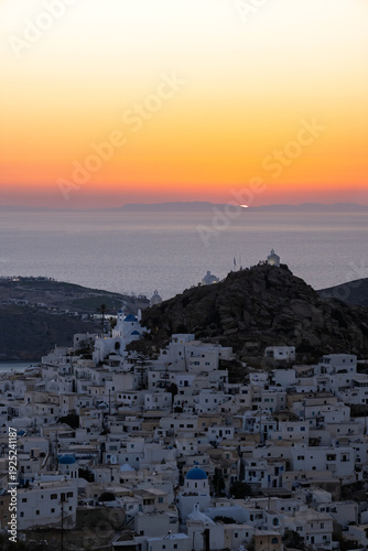 Panoramic view of the beautiful whitewashed village also known as chora, in Ios Greece, and a spectacular orange sunset in the background