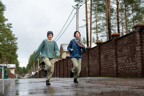 Vászonkép A determined teenage girl and boy run forward through slushy street conditions