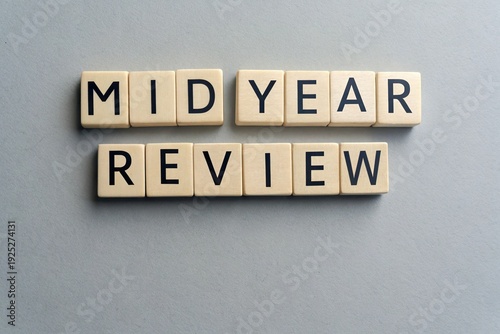 Mid-year review spelled out in wooden blocks on a gray background, symbolizing reflection and assessment