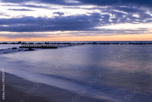 Amazing colourful sunrise seen over the Mediterranean Sea from Barceloneta Beach, which is located next to Barcelona's classic fishing quarter. It is the cities oldest and best-loved beach and gives w