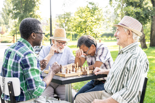 Foto Group of senior friends playing chess at the park
