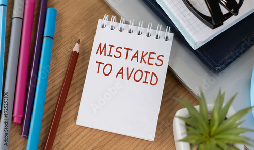 Tableau sur toile MISTAKES TO AVOID text written in red on a spiral notepad on a wooden desk with office supplies