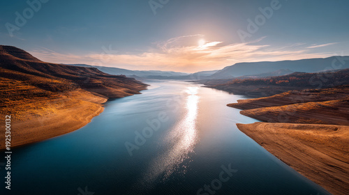 Solar glare over a vast, empty reservoir with exposed bed. Water crisis and water shortages in summer during prolonged drought.
