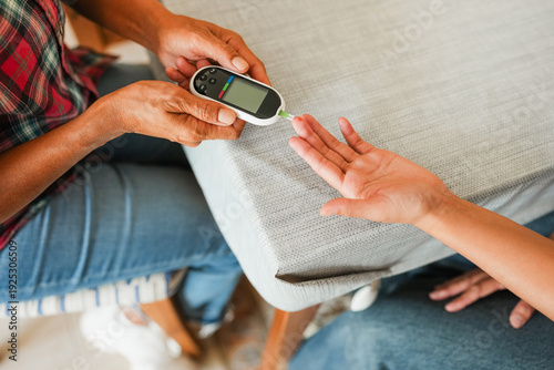 Фотография Mother makes blood glycemia test to her daughter for diabetes check at home - Me