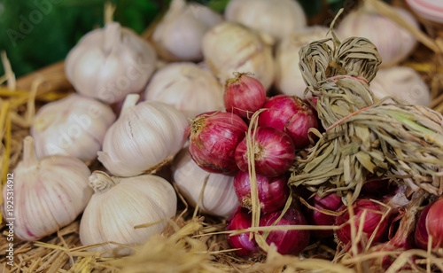 A rustic basket filled with fresh garlic bulbs and purple shallots, showcasing natural textures and earthy tones, perfect for cooking, food photography, and adding rich flavor to homemade dishes.