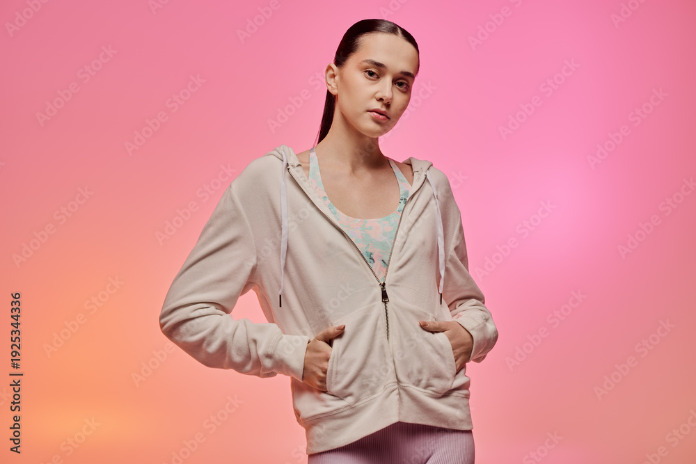 Obraz premium Stylish young woman in trendy activewear against a vibrant pink background showcasing modern fashion