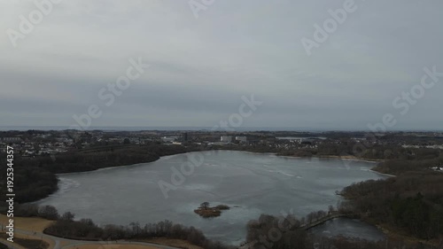 Wallpaper Mural Aerial drone footage showing a frozen lake captured at midday. The scene features ice-covered water surfaces under direct daylight, highlighting textures, open surroundings, and clear winter condition Torontodigital.ca