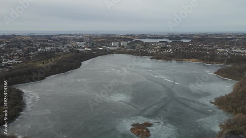 Wallpaper Mural Aerial drone footage showing a frozen lake captured at midday. The scene features ice-covered water surfaces under direct daylight, highlighting textures, open surroundings, and clear winter condition Torontodigital.ca
