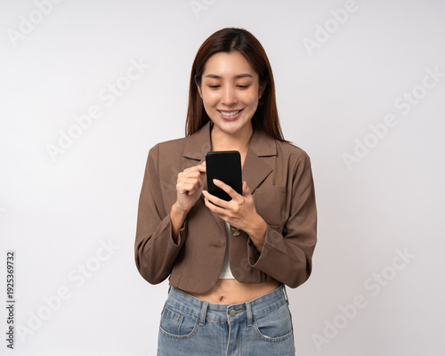 Pretty young asian woman using cellphone standing on isolated white background. Happy Excited Beautiful young asian shopping online payment with mobile phone. Playing game on smartphone