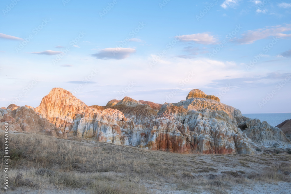 Fototapeta premium Scenic panorama of Cape Shekelmes on the shore of Lake Zaisan in East Kazakhstan region. Unique clay canyons with bright stripes of ochre
