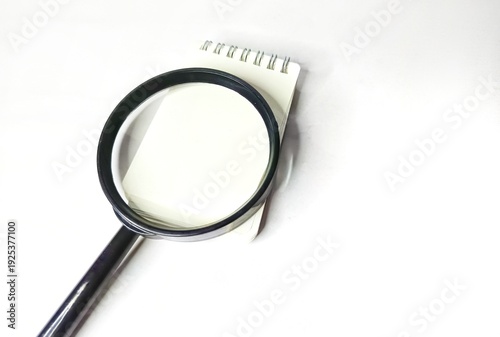 Magnifying glass and blank notebook on white background