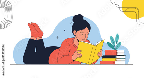 Young woman lying on her stomach on the floor while reading a yellow book next to a tall stack of colorful textbooks at home.