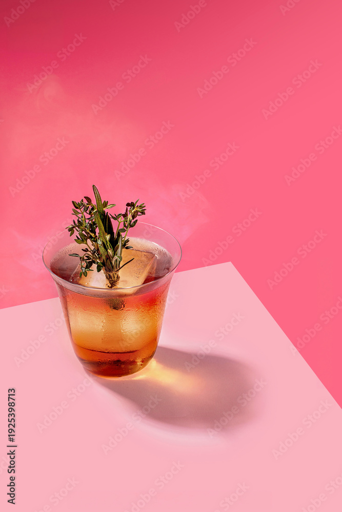 Obraz premium Smoked Old Fashioned Cocktail with Large Ice Cube and Fresh Rosemary Thyme Garnish