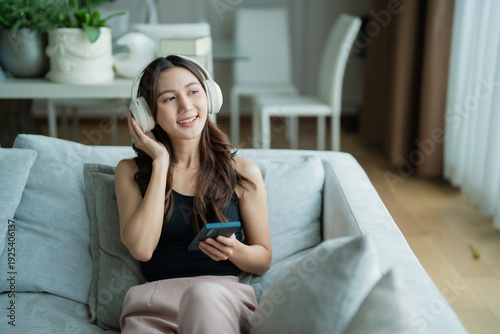 Foto Young woman relaxing on a comfortable sofa in her living room, happily listening
