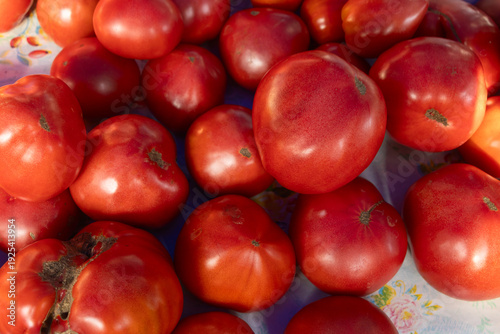 Ripe red tomatoes in close view. Fresh tomatoes with shiny skins and natural texture captured in vibrant light for culinary and agricultural themes