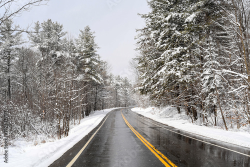 Moment of winter driving on a road lined with snow-covered trees in the Laurentians of Quebec