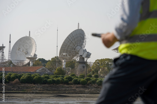 Schilderij op canvas Satellite dish array with ground station equipment and on-site personnel in outd