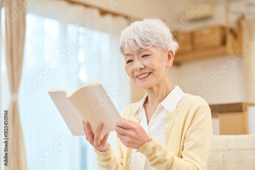 Foto リビングで読書をするアジア人シニア女性
