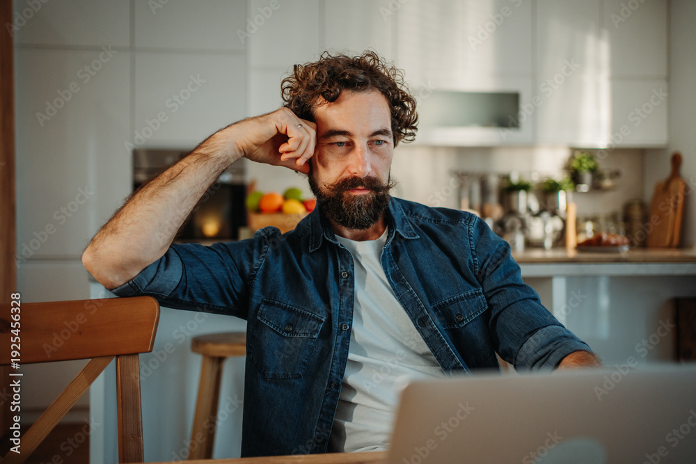Fototapeta premium Man working remotely at home feeling tired and thoughtful