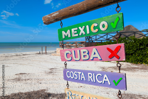 Wooden beach signs in Holbox with red cross over Cuba