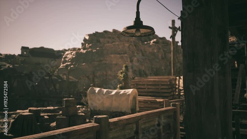 A vintage lamp hangs near wooden structures at a mining site surrounded by rugged mountains. The setting reflects an old world charm with rustic elements under a clear sky.