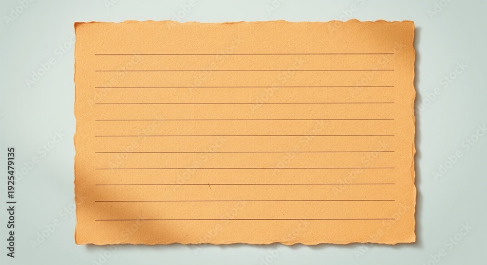 Fototapeta premium A piece of orange lined paper with rough, torn deckle edges on a light blue-grey surface.