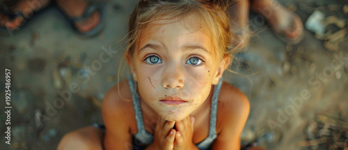A girl with sad eyes and a dirty face against a backdrop of dirt, reflecting the consequences of social upheaval or environmental disasters, will serve as a powerful backdrop 