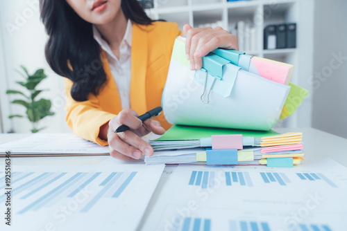 Analyzing Papers: Focused hands meticulously sift through colorful documents and charts at a desk, the scene exudes precision and attention to detail. 