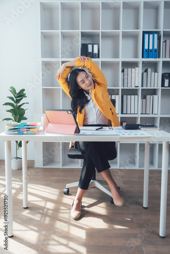 Office Serenity: An office worker, draped in a sunny yellow blazer, stretches at her desk in a moment of calm, surrounded by a productive office environment.
