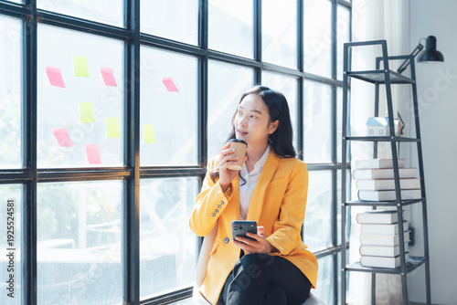 Woman in Thoughtful Moment: An image of a focused female, engrossed in contemplation while holding a coffee cup near a glass window. She finds a brief moment of peace with the coffee cup. 