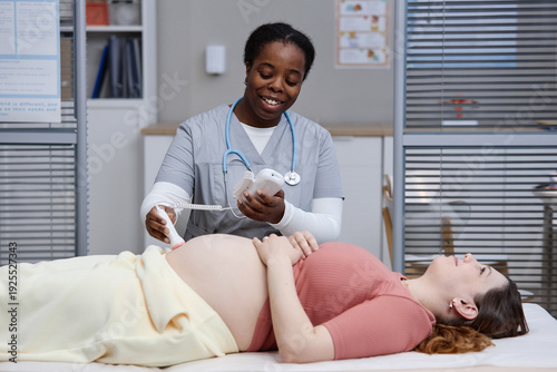 Valokuva Black woman medical professional performing ultrasound scan on pregnant Caucasia