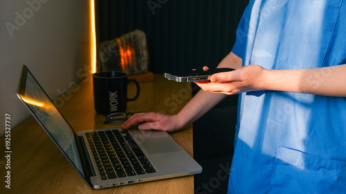 Healthcare professional using laptop and smartphone for medical tasks