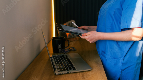 Healthcare professional using digital tablet and laptop for remote patient care and medical record management