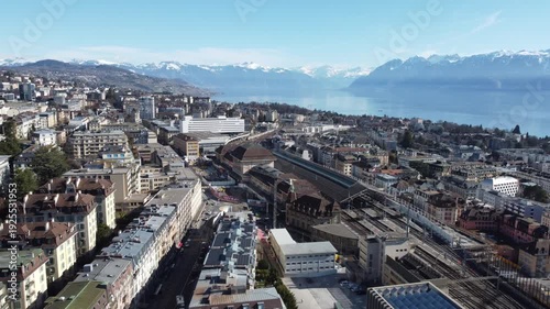 Drone flying toward Lausanne train station with Lake Geneva and Alps