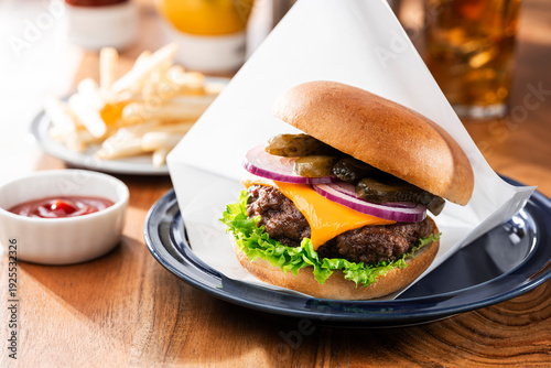 ワックスペーパーに包まれたチーズバーガーとフライドポテトとコーラ