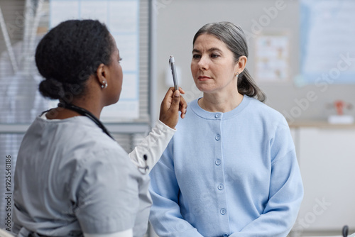 Cuadro en lienzo Middle aged Caucasian woman sitting while Black female doctor performing eye mov