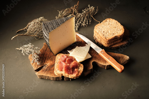 Bild auf Leinwand Cheese and Bread Served on a Wooden Board With a Knife and Garnish