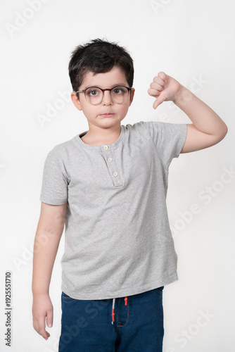 Young boy with glasses giving a thumbs down gesture on a white background