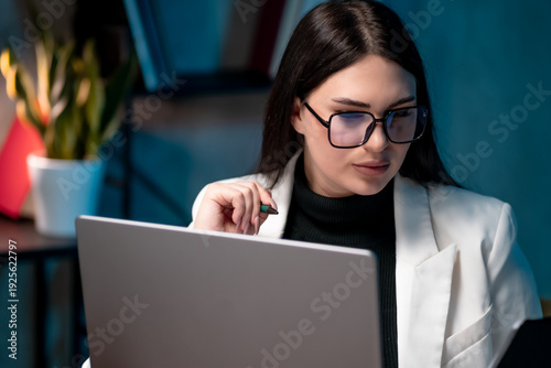 Concentrated female manager working alone in a modern office workspace, carefully reviewing paperwork and planning next steps. Leadership, corporate strategy, professional focus concept.
