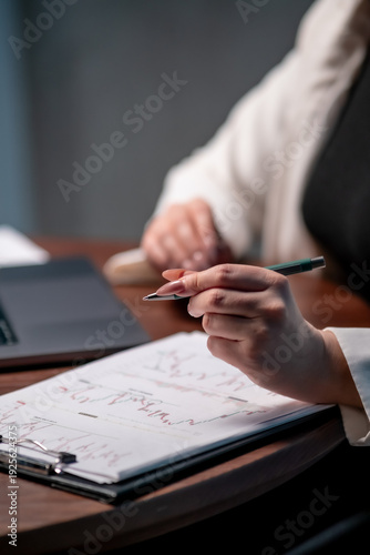 Businesswoman working on laptop with charts showing company revenue trends. Financial analysis, business management and productivity concept.
