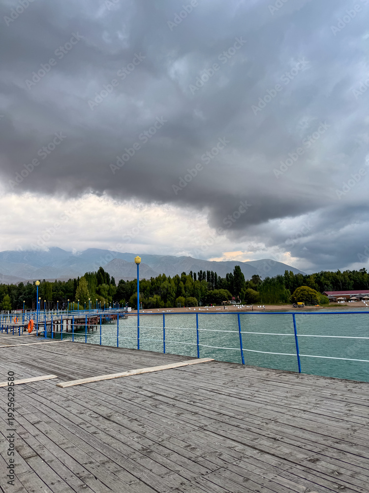 Fototapeta premium Pier at Issyk Kul Lake in Kyrgyzstan. Calm water surface, minimal composition and warm sunset light.