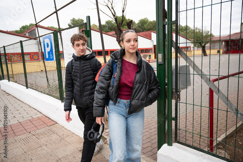 Tableau sur toile Teenage girl leaving high school with male friend after classes showing friendsh