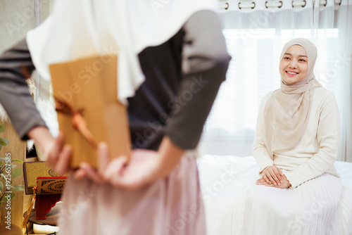 Asian Muslim daughter giving gift surprise to mother indoor family moment